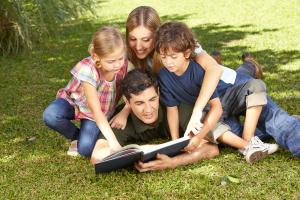 Familie beim Lesen vom Buch im Garten